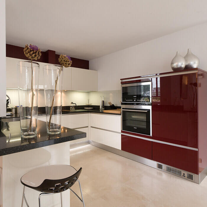 Strakke greeploze keuken in hoogglans wit gecombineerd met bordeaux rood