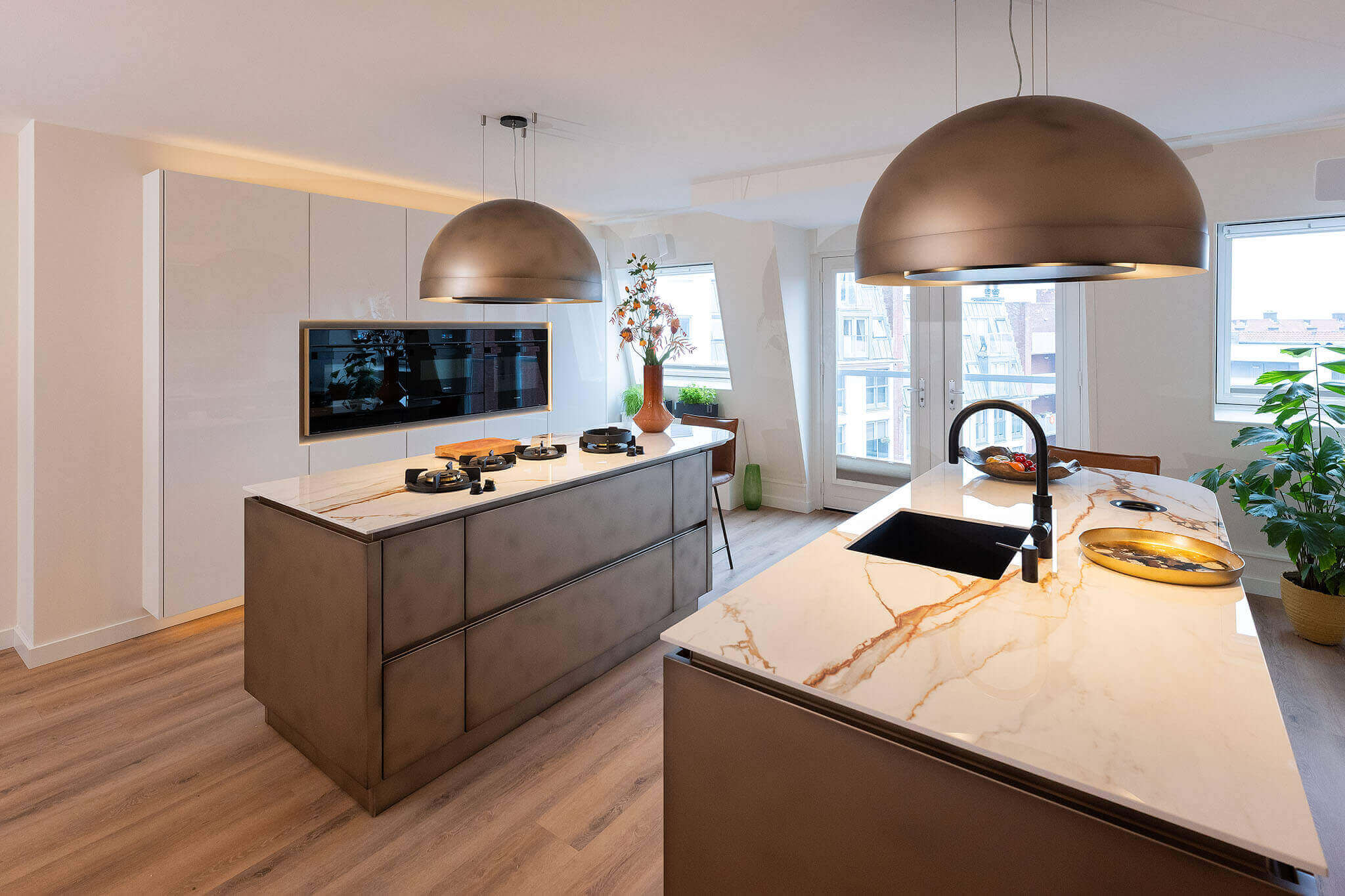 Exclusieve maatwerk keuken in Rotterdam met dubbel kookeiland, marmeren bladen en bronzen designlampen