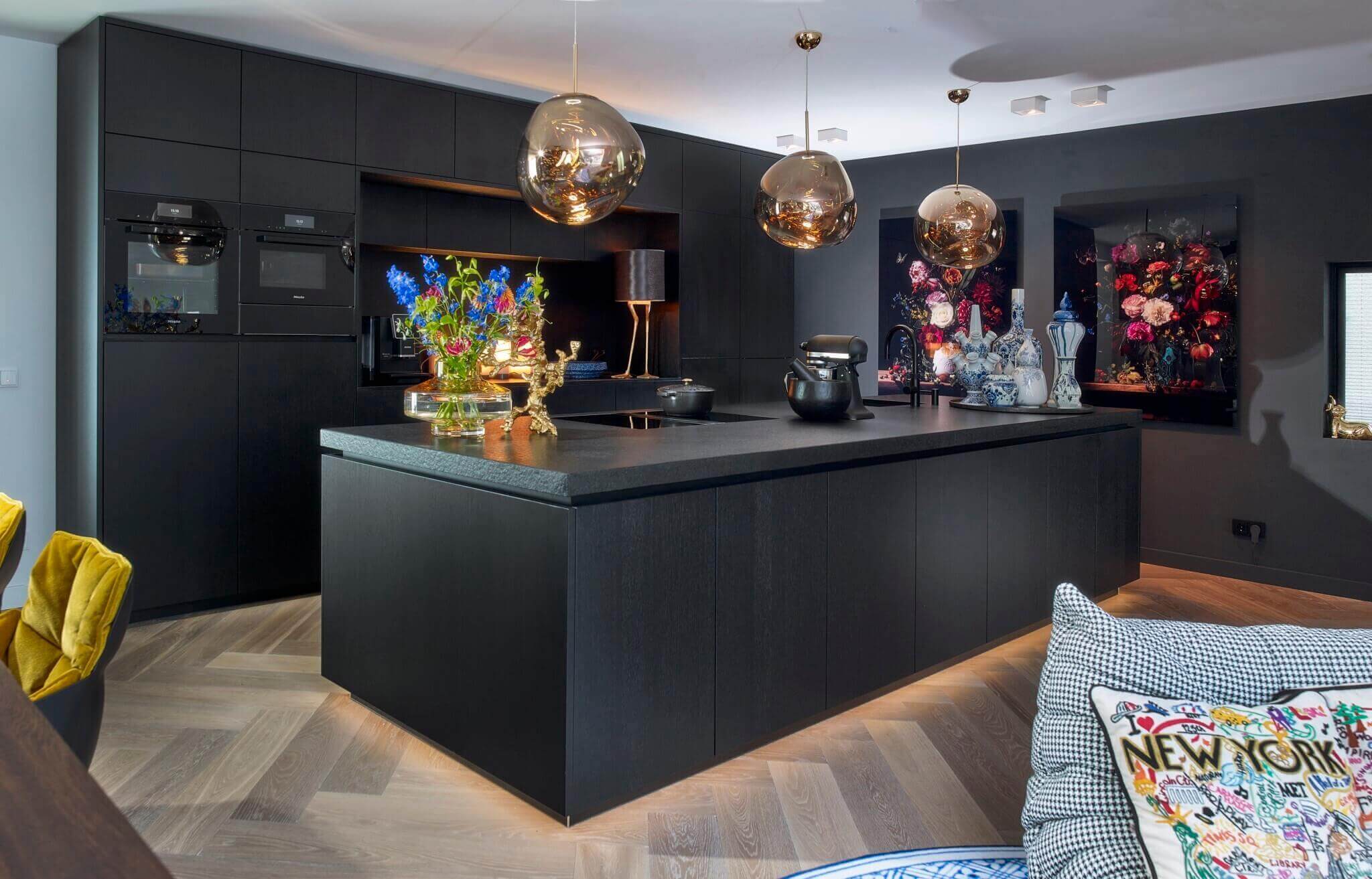 Luxe zwarte designkeuken op maat in Rotterdam met kookeiland en gouden hanglampen