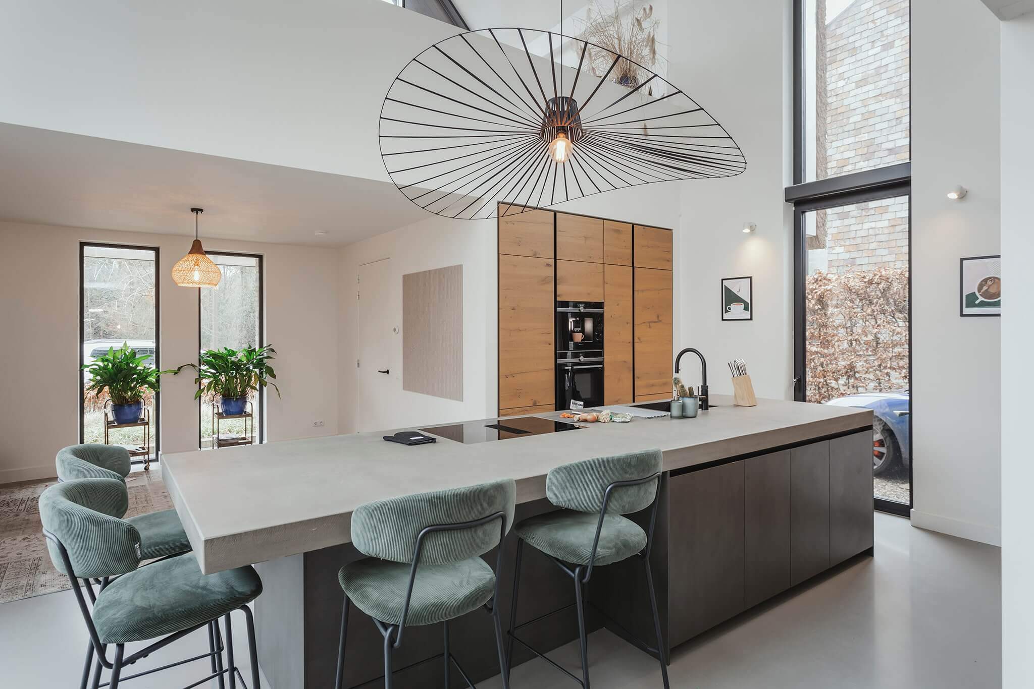 Luxe Tieleman-keuken van het merk Keller met een groot kookeiland met betonnen werkblad en barstoelen