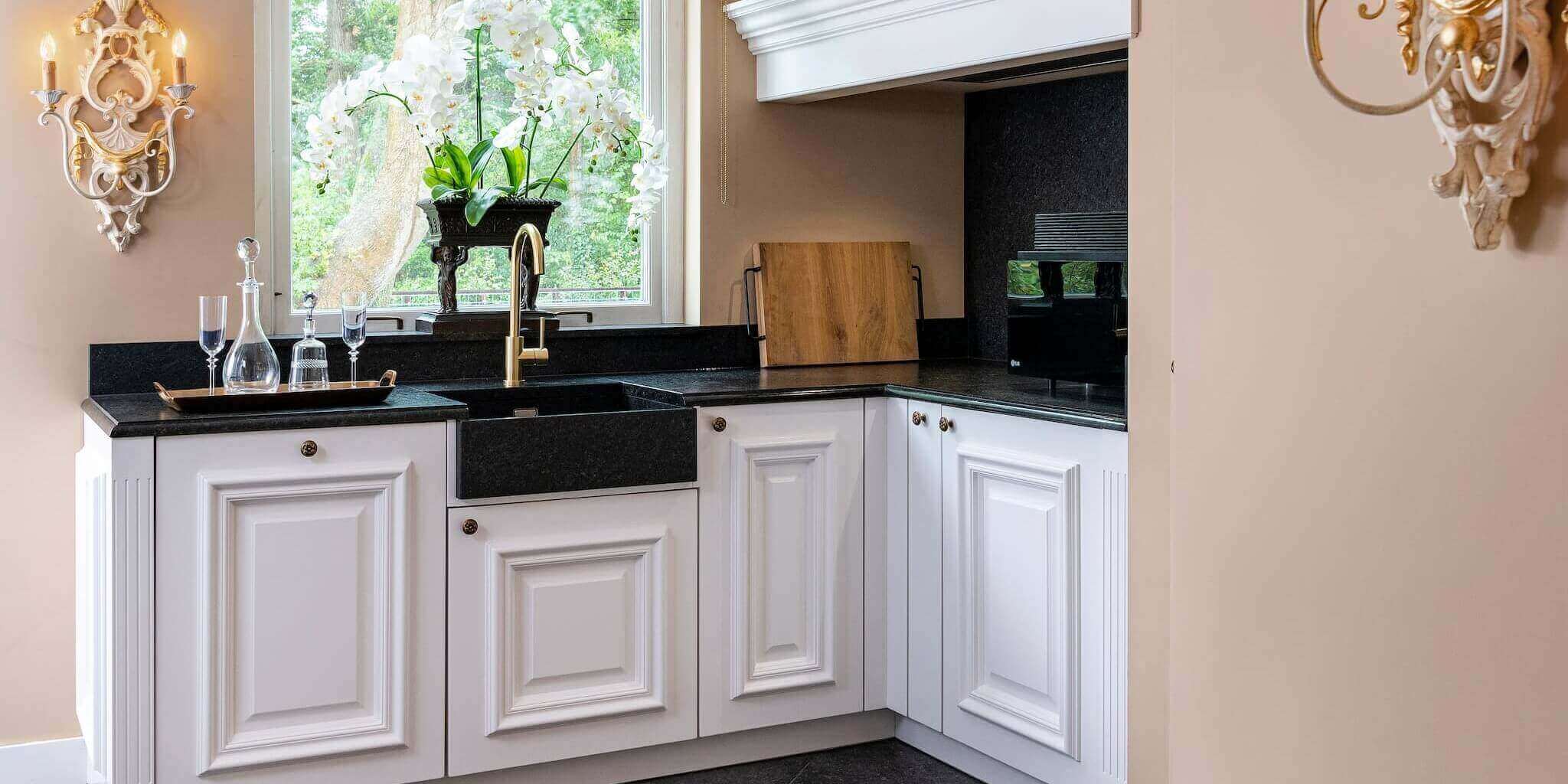 Luxe witte Mereno-keuken met een Boretti fornuis en zwart blad.