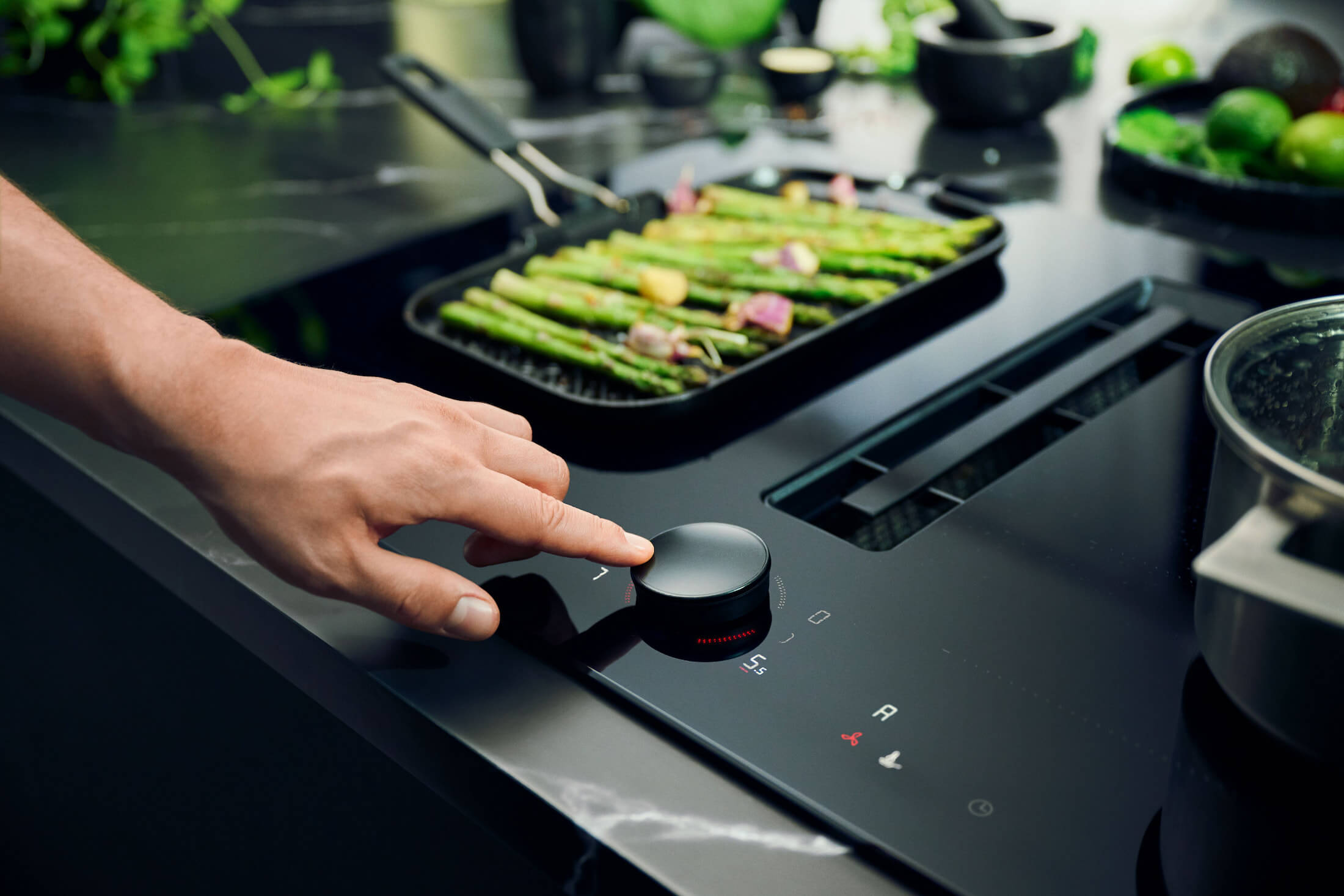 Close-up van de krasbestendige NEFF matzwarte inductiekookplaat met afzuiging en de afneembare TwistPad bedieningsknop.