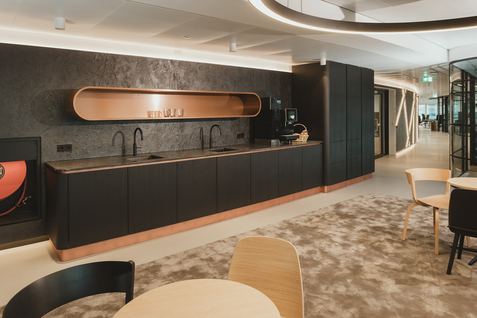 Moderne bedrijfskeuken met zwarte Mereno-fronten, koperen details en granieten aanrechtblad geplaatst door Tieleman Keukens
