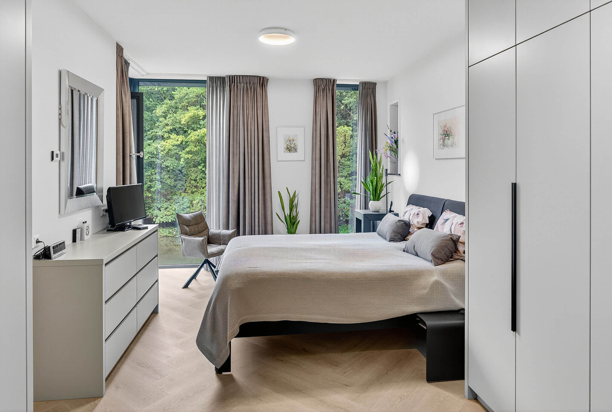 Grote kledingkasten die van de vloer tot het plafond lopen en precies op maat zijn gemaakt voor de slaapkamer.