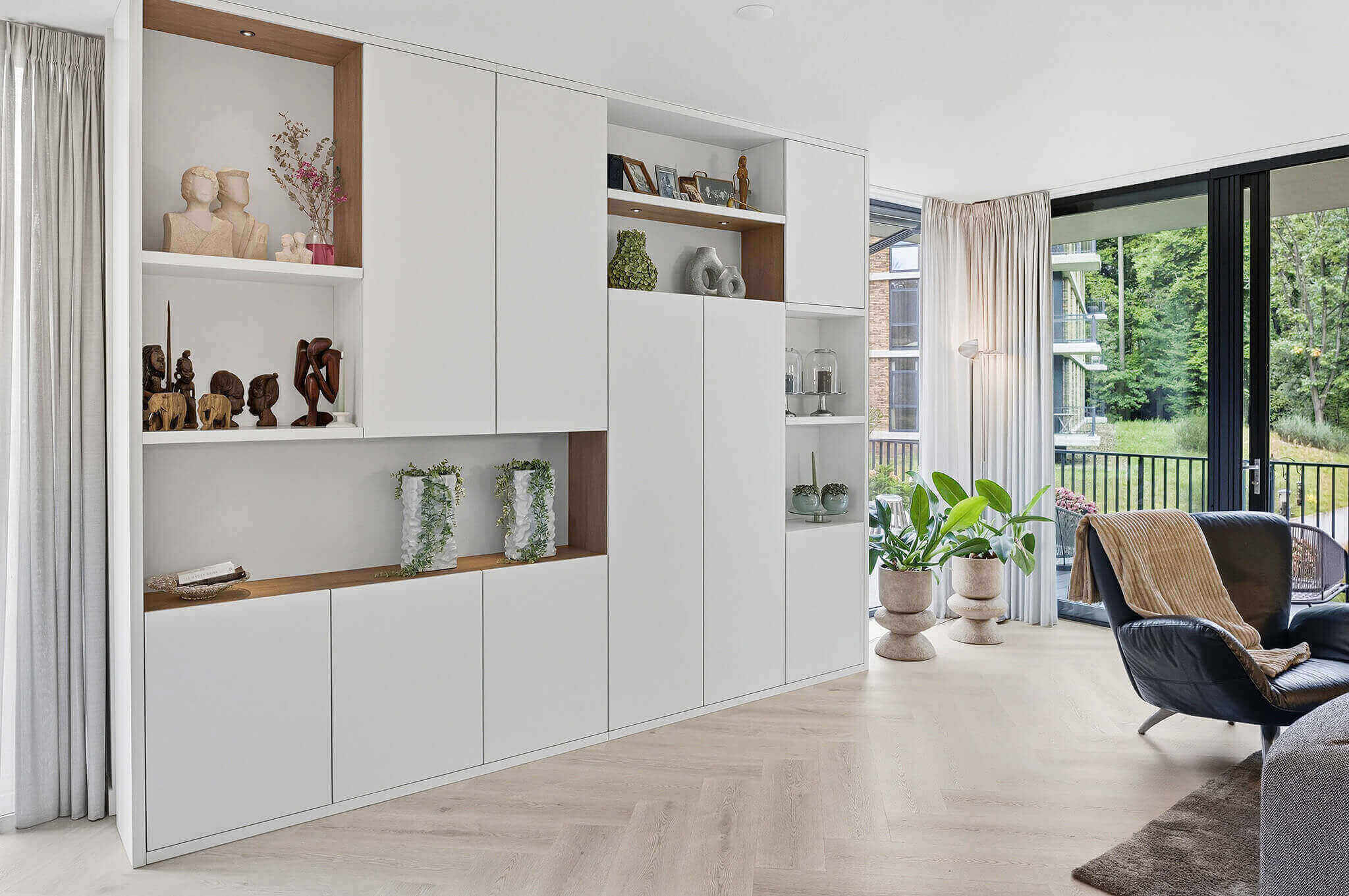 Een maatwerk woonkamerkast in wit en hout die rust uitstraalt.