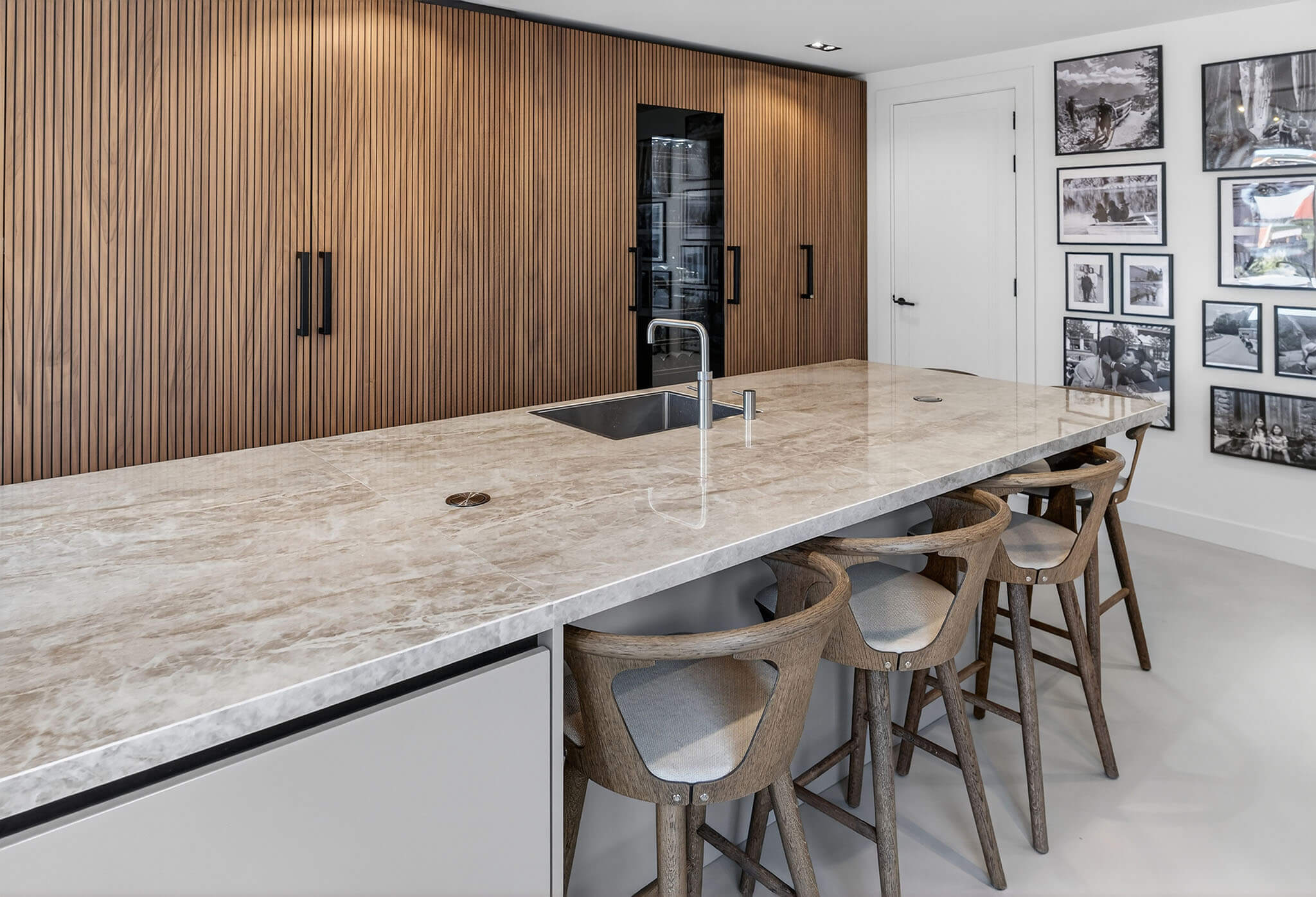 Luxe Tieleman-keuken met een houten kastenwand van verticale noten lamellen.