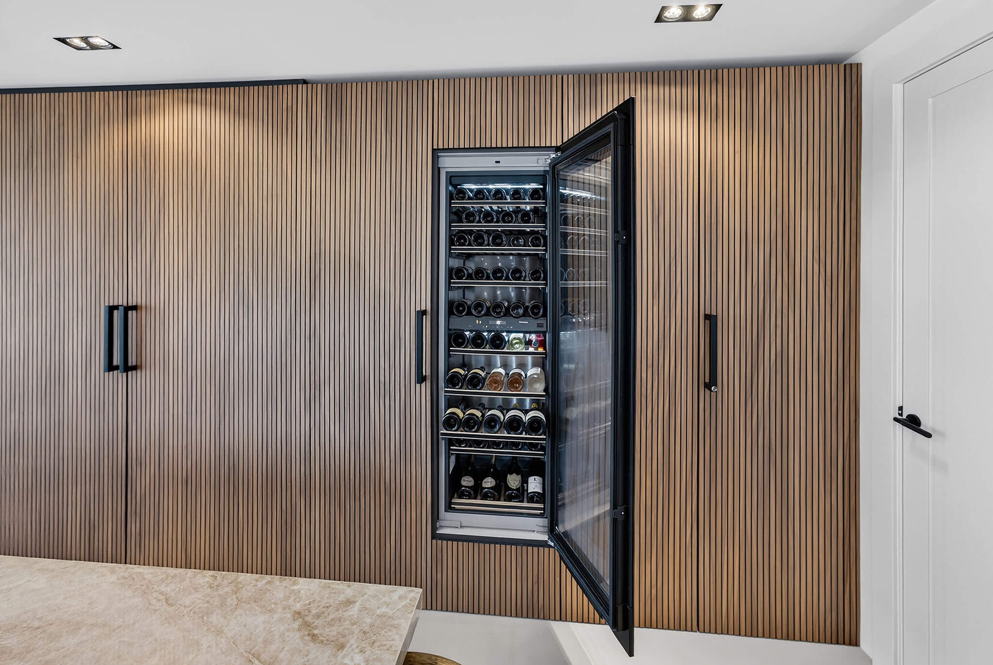 Grote ingebouwde Miele wijnklimaatkast in een luxe noten houten kastenwand.
