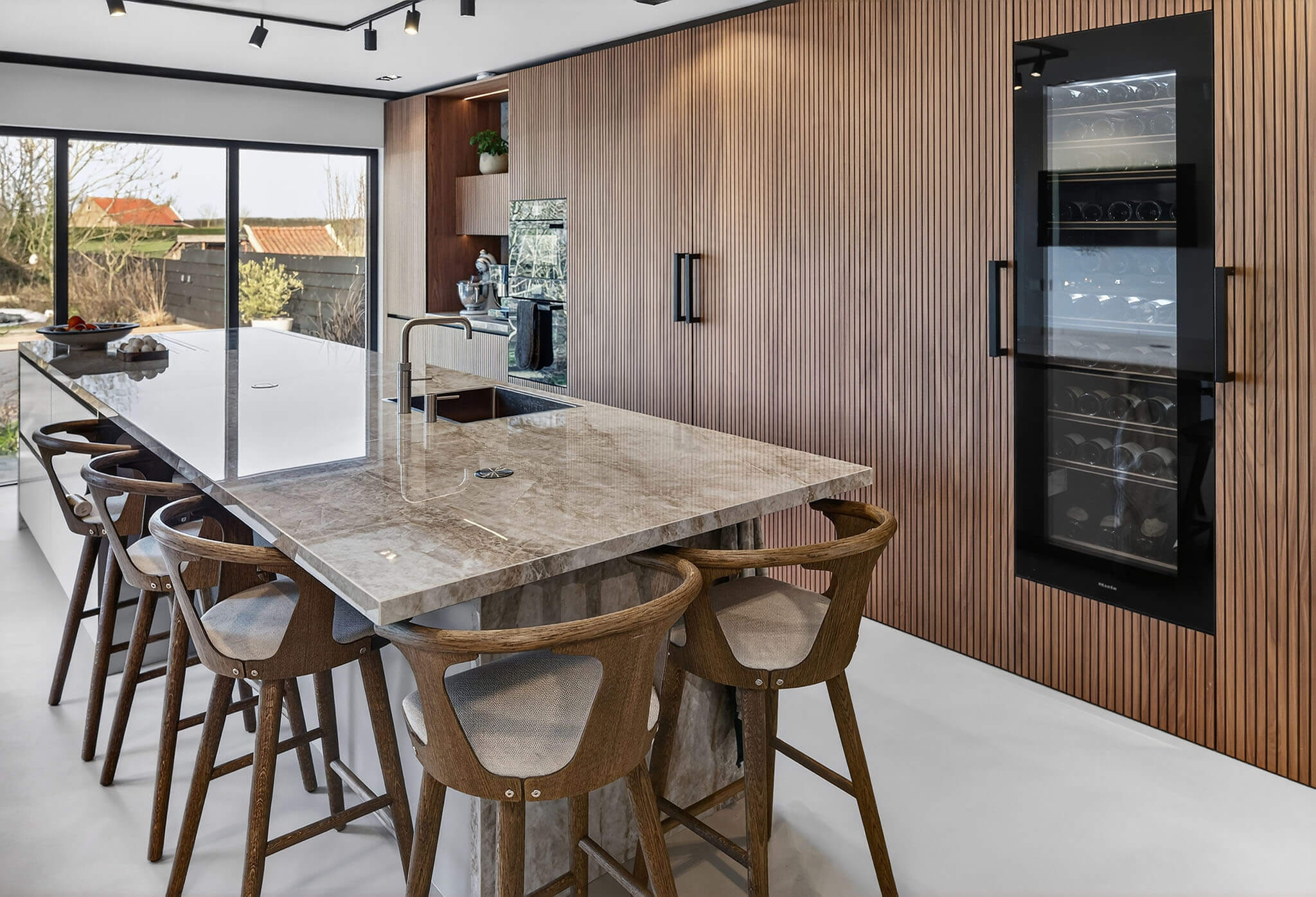 Design keuken met een gezellige houten bar en zitgedeelte aan het marmeren eiland.