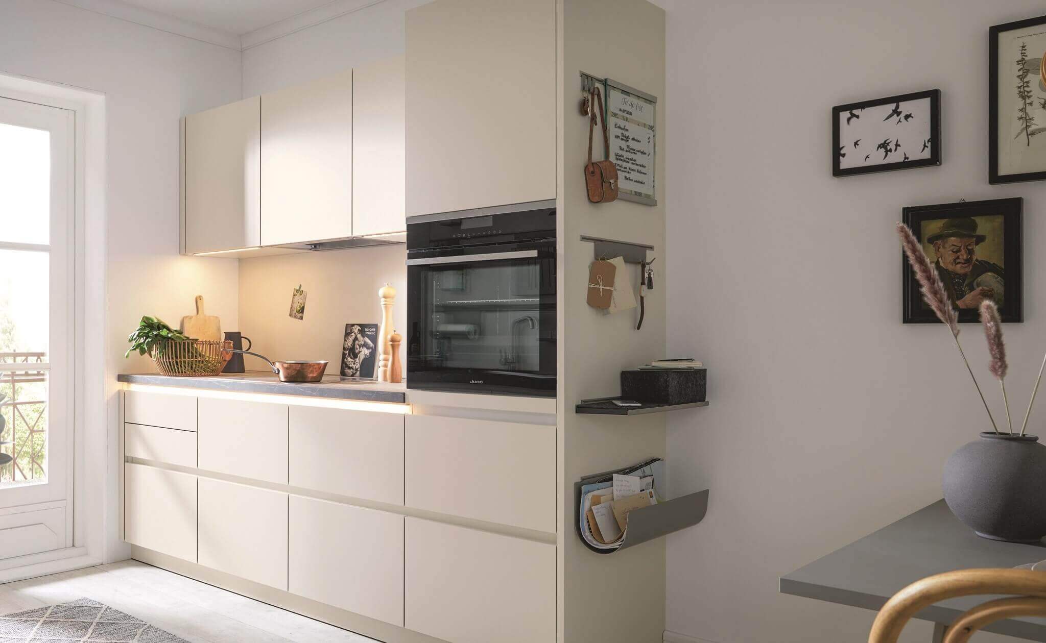 Strakke greeploze keuken van 3 meter in beige met een ingebouwde oven op ooghoogte en sfeervolle led-verlichting