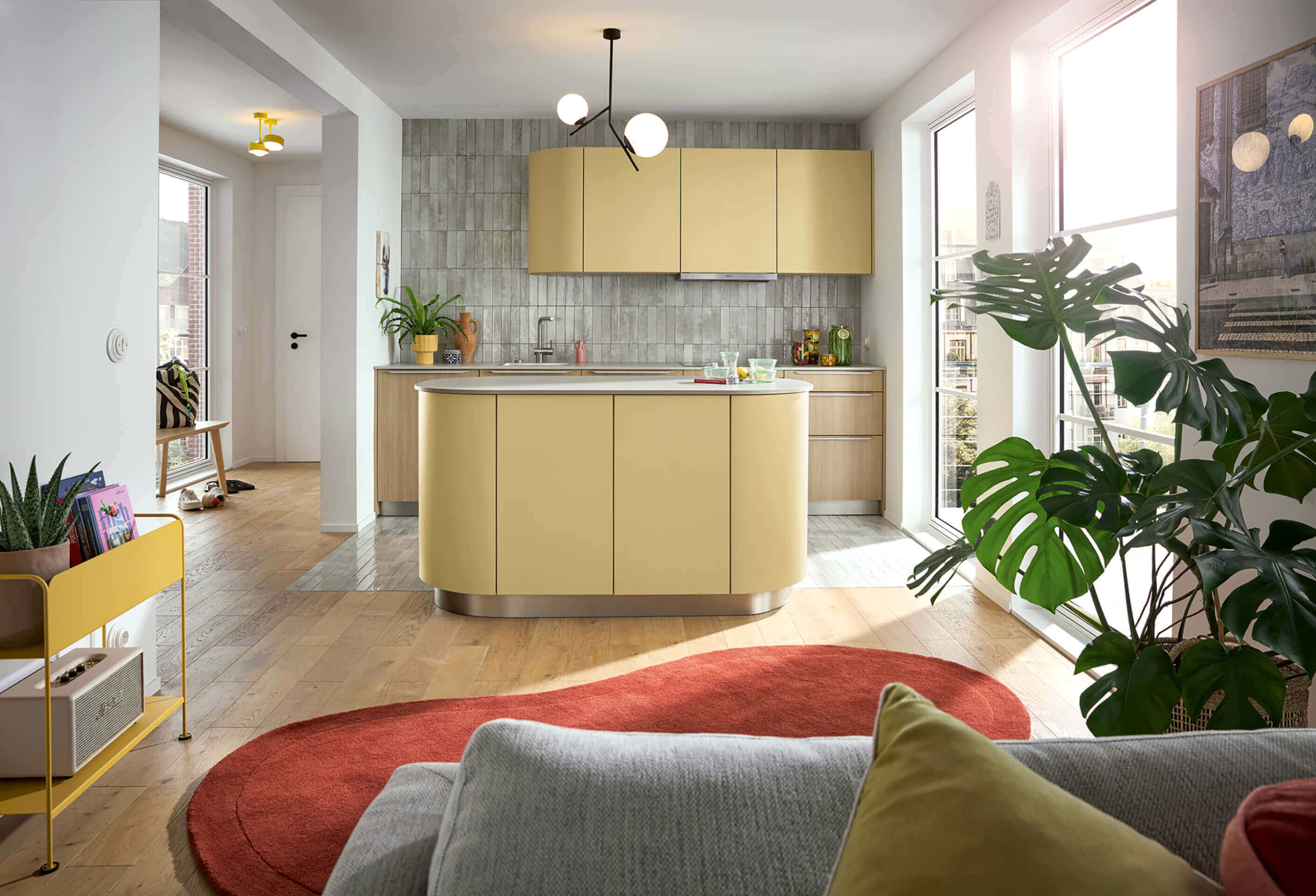 Moderne open keuken van 3 meter met pastelgele kasten, houten elementen en een afgerond kookeiland