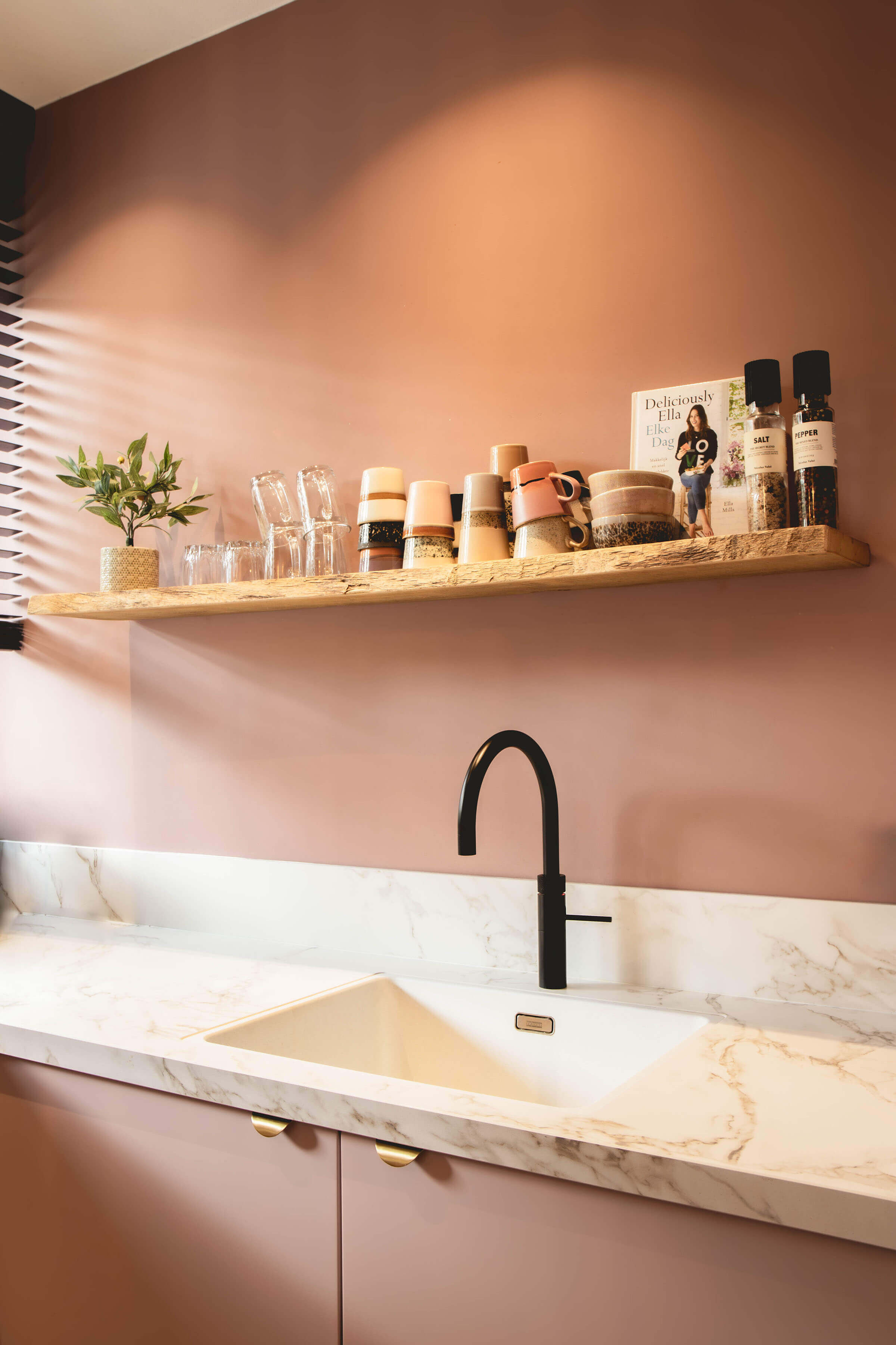 Ideale indeling van een keuken van 3 meter met een marmerlook werkblad, zwarte kraan en houten wandschap tegen een oudroze muur